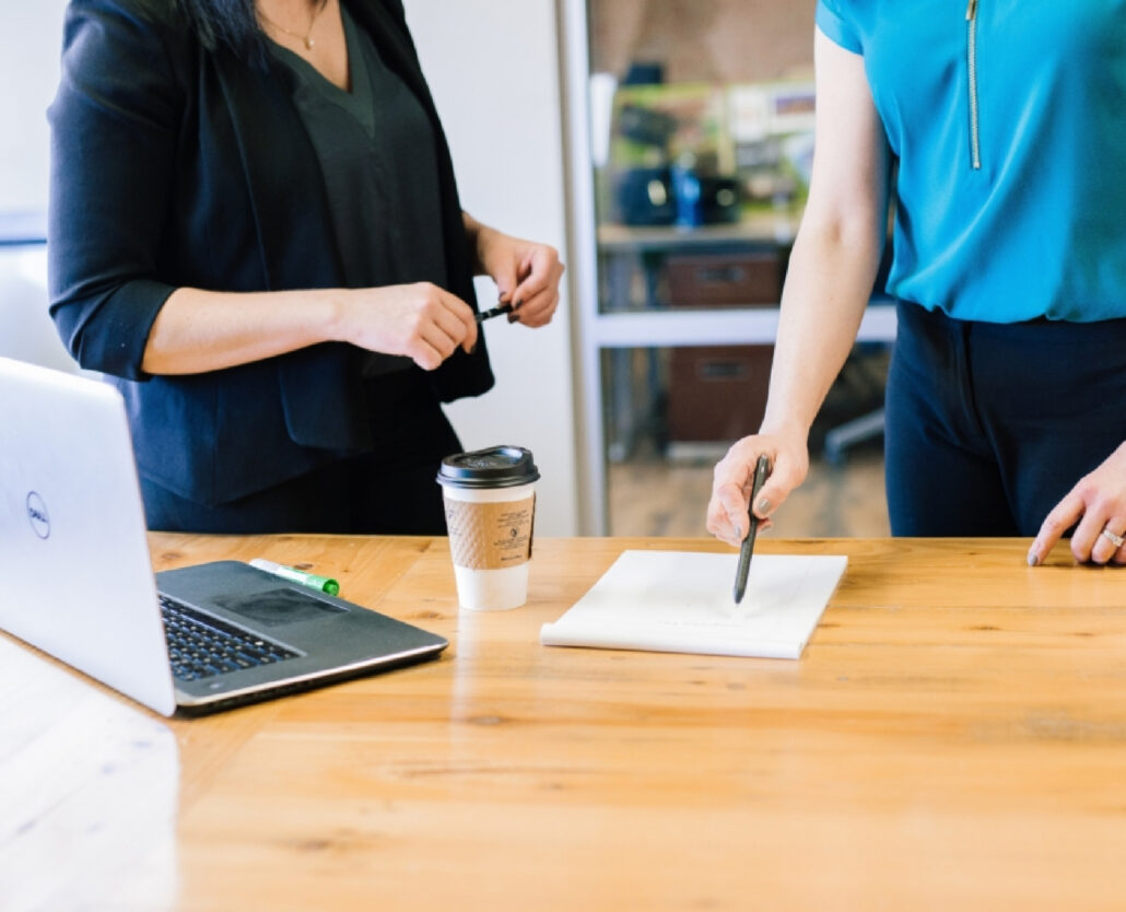 Two coworkers reviewing notes at a desk