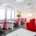 An office showcasing two parallel rows of office desks. There is a red chair and a computer at each station.