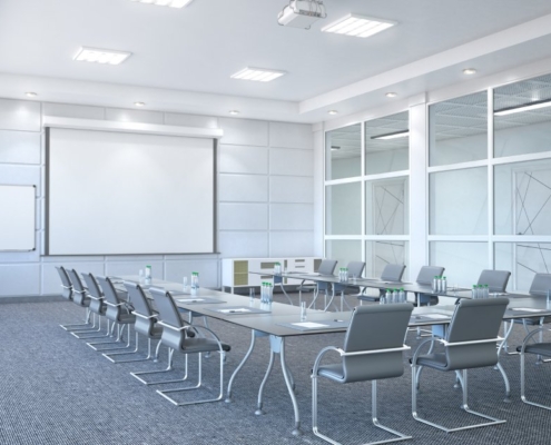 A large conference room with the table and chairs in a U-shaped layout. A projector and whiteboard are in the front of the room.