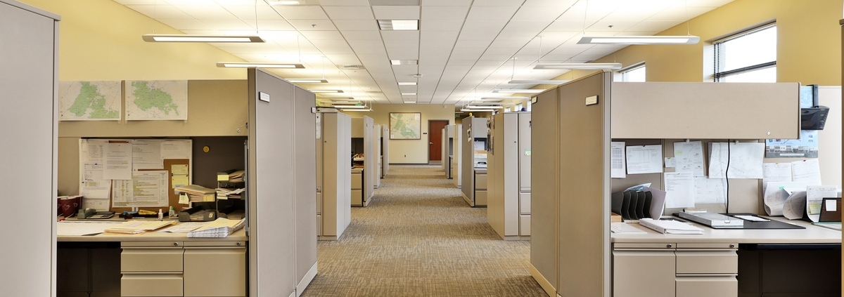 A modern office with several cubicles on either end of a makeshift hallway. The cubicles are filled with personal items.