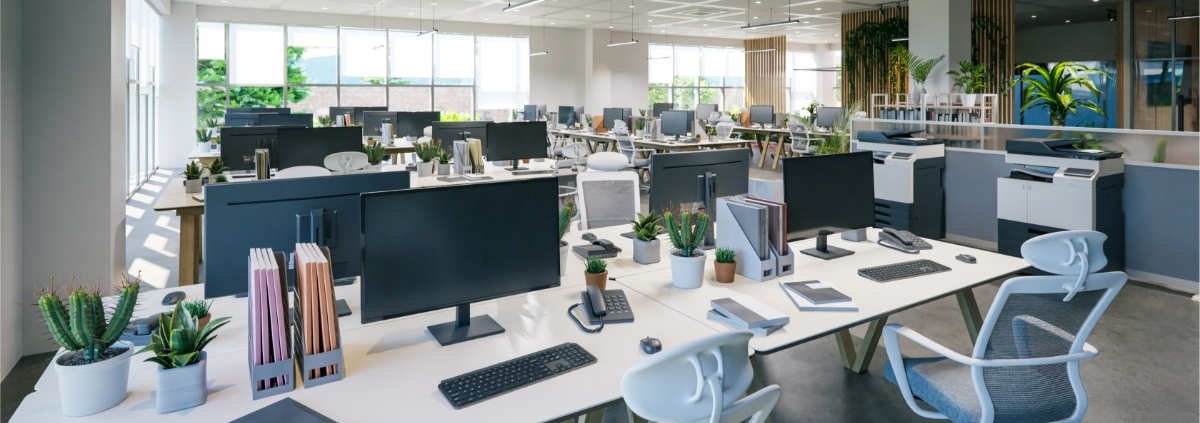 A modern office space with several workspaces spread out. Each desk has a monitor, phone, and chair.