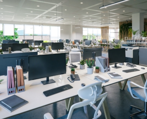 A modern office space with several workspaces spread out. Each desk has a monitor, phone, and chair.