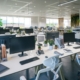A modern office space with several workspaces spread out. Each desk has a monitor, phone, and chair.