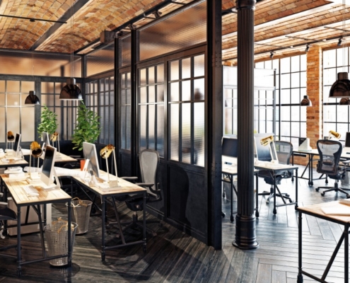 There is a large room with a partition in the middle separating the two halves of the room. Each side has desks and chairs.