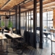 There is a large room with a partition in the middle separating the two halves of the room. Each side has desks and chairs.