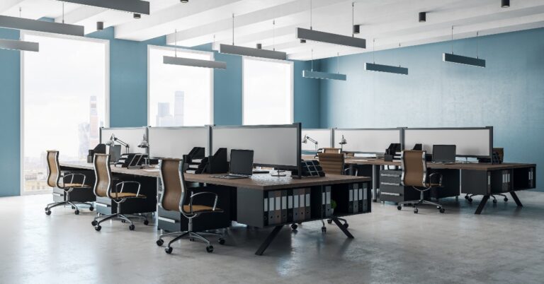 An interior office space with several desks and chairs. There is a window along the wall letting sunlight in.